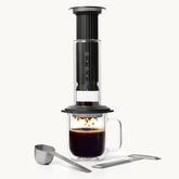 Coffee maker with glass mug and coffee beans on a white background