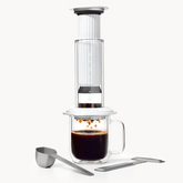 Coffee maker with glass carafe and metal scoop on a white background