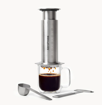 AeroPress coffee maker with a glass of brewed coffee on a white background